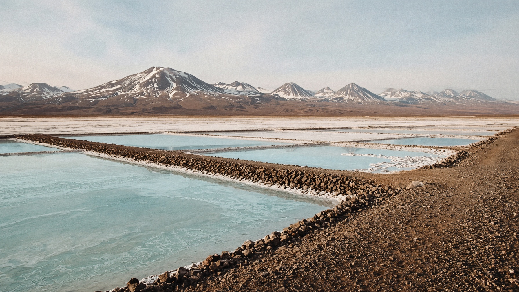 Operación de salmuera de litio en la Puna argentina, pozas pálidas y volcanes al fondo.